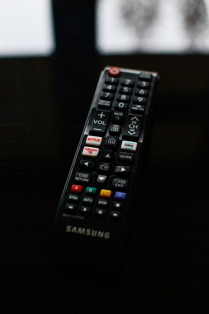 A detailed close-up of a Samsung TV remote resting on a dark surface, emphasizing its buttons and design.