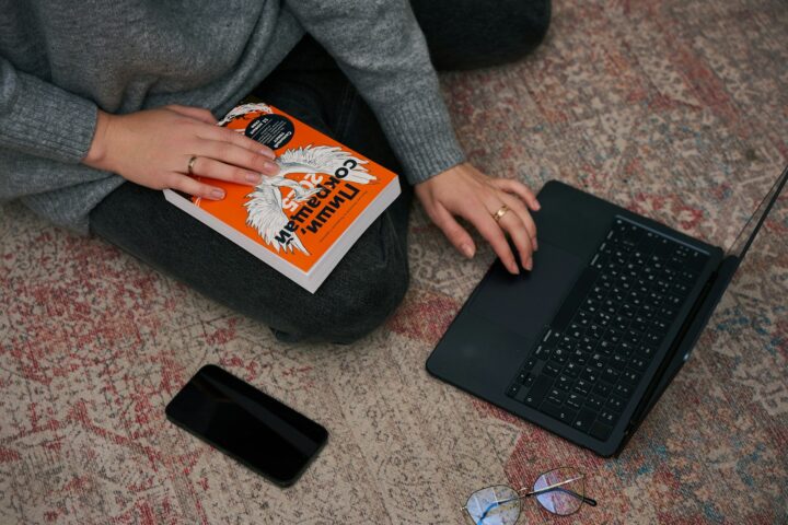 a person sitting on the floor with a book and a laptop