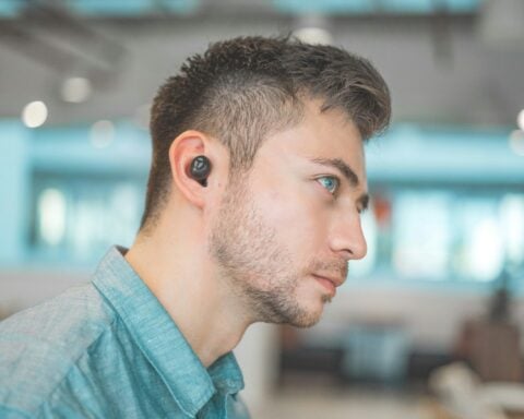 man wearing blue dress shirt with black Bluetooth earbuds