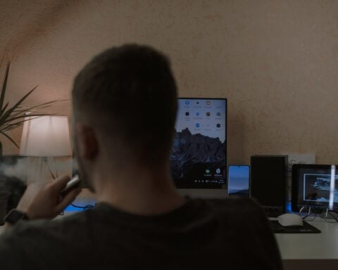 a man smoking a cigarette in front of a computer