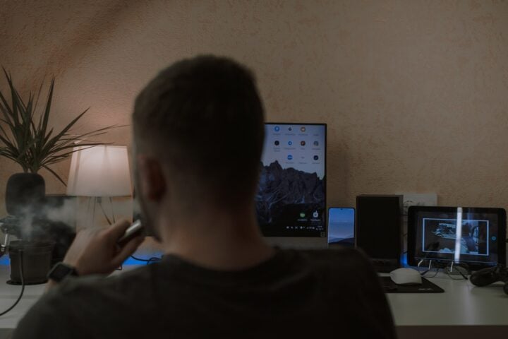 a man smoking a cigarette in front of a computer