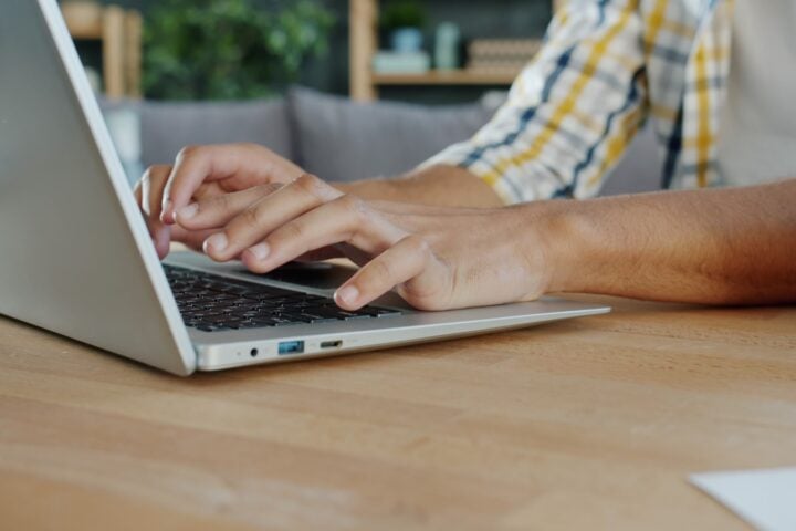 Hands typing on a laptop computer keyboard.