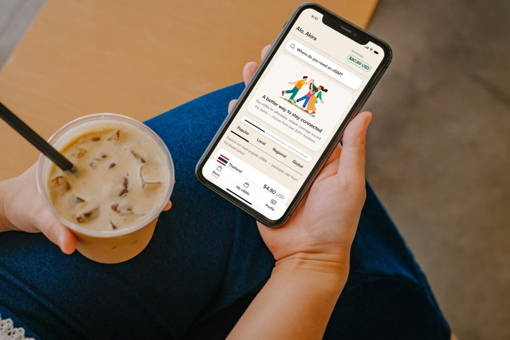 Person holding phone with app and iced coffee