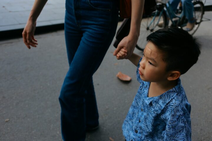 Child holding adult's hand walking on street