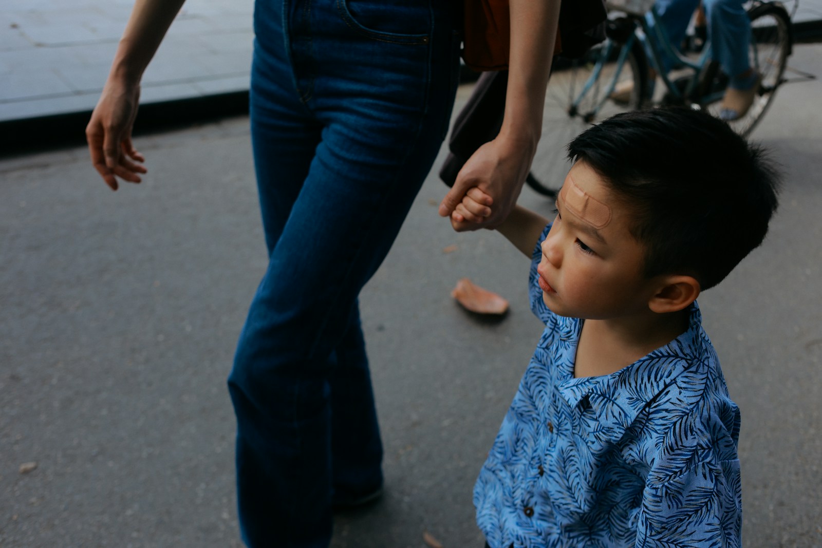 Child holding adult's hand walking on street