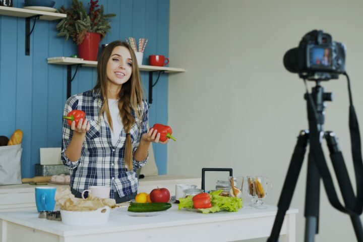 Woman filming cooking tutorial with fresh vegetables