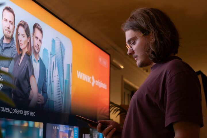 Man watching TV holding a smartphone