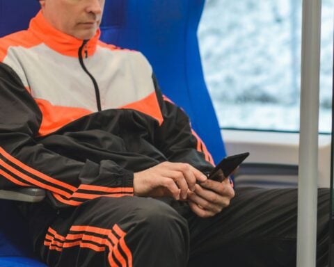man in orange and black jacket and black pants sitting on blue chair