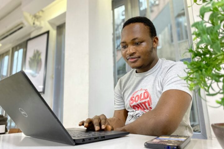 man in white and red crew neck t-shirt using laptop computer