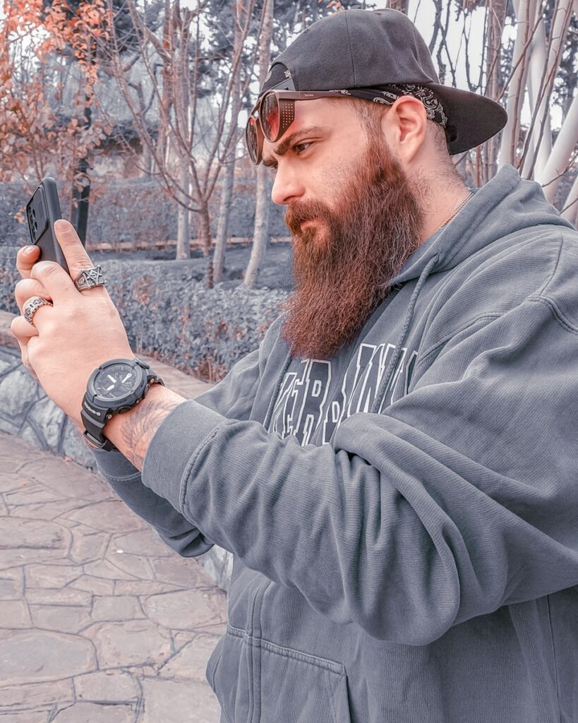 a man with a beard is looking at his cell phone