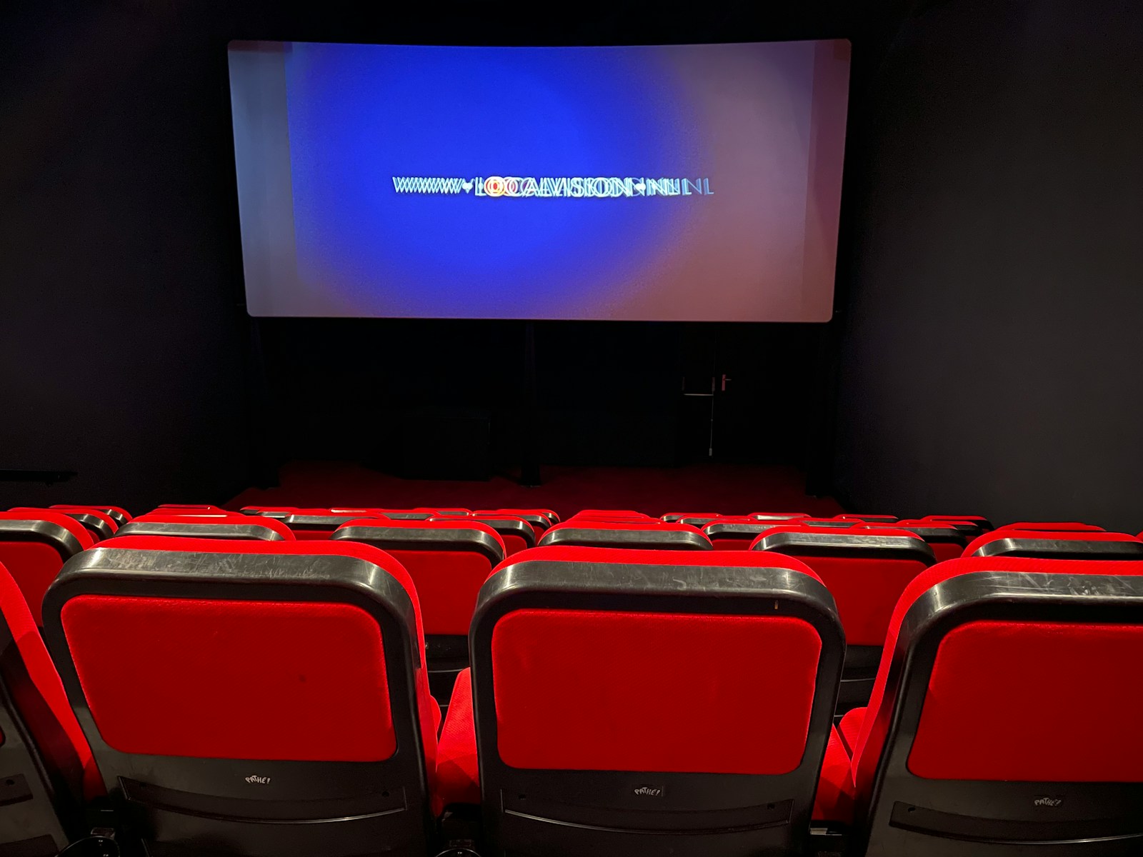 a theater with red seats and a projector screen