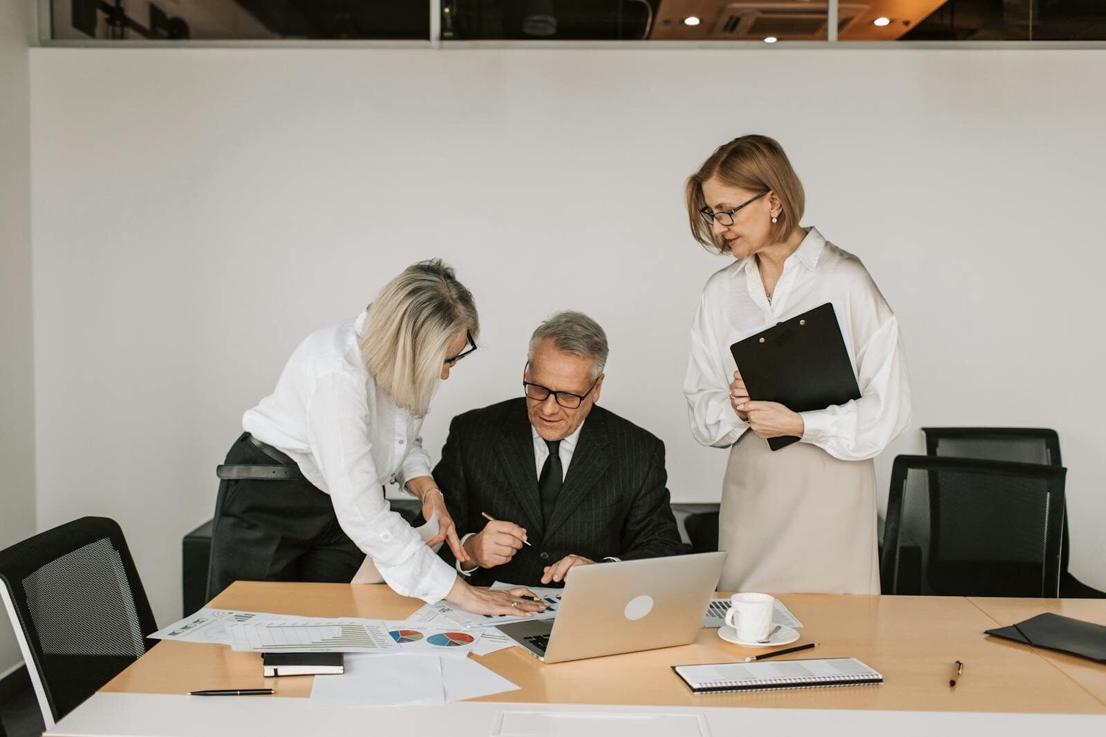 Elderly man and two women collaborating in a modern office setting.
